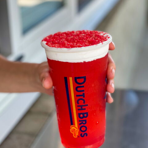 A red, iced, Dutch Bros Rebel Energy drink is handed out the drive thru window