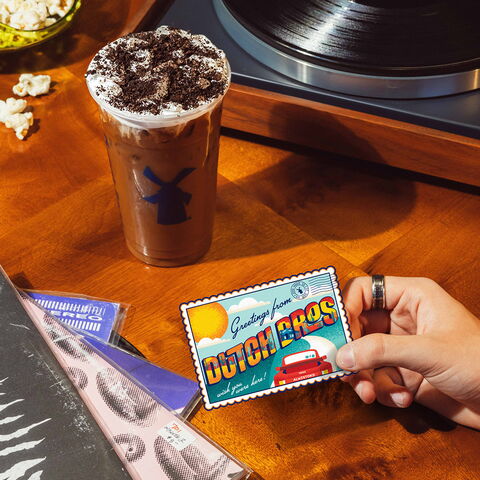 A desk with an iced cookie drink and stickers from Dutch Bros